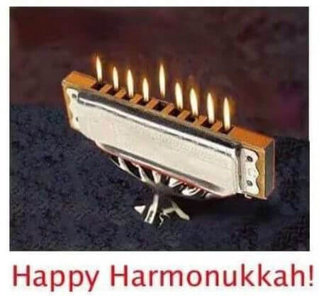 Photo of harmonica on a stand with nine flames coming out of the nine holes and caption: Happy Harmonukkah!