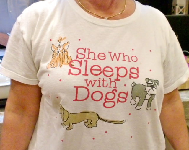 Woman wearing T-shirt with funny saying: She who sleeps with dogs